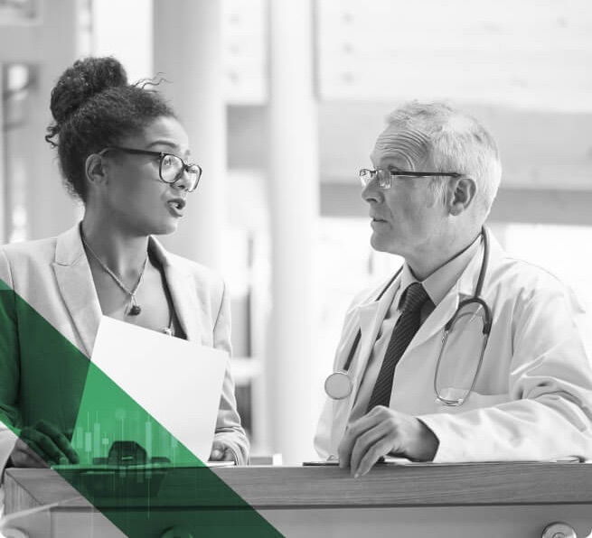 A consultant holding a paper document advises the medical professional sitting next to her.