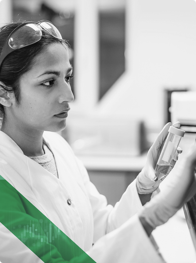 A scientist holding a sample container verifies the accuracy of information on a computer screen.