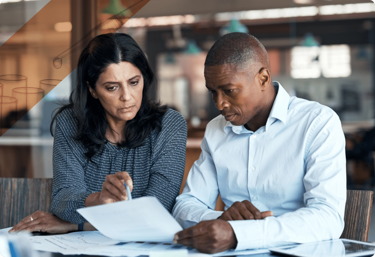 Two professionals at a table reviewing a document containing regulatory information.