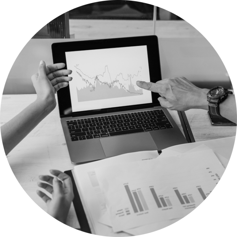 The hands of two data scientists gesture at a screen and papers showing clinical trial data, as if in conversation.